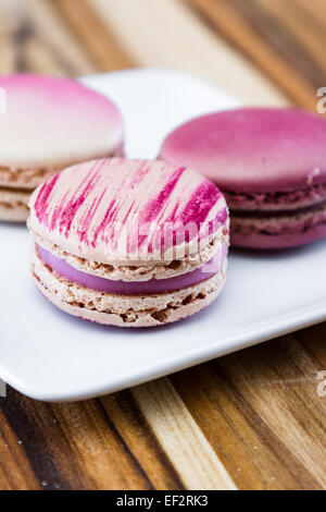 französische Macarons auf einem weißen Teller in einer Vielzahl von rosa Farben und Aromen Stockfoto