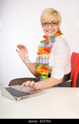 Blonde Frau, die Eingabe auf Laptop während des Tragens ein lei Stockfoto