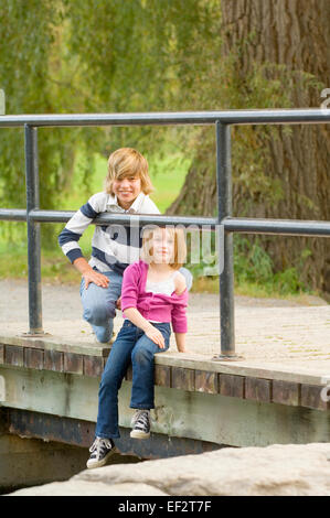 Geschwister, die sitzen auf Brücke Stockfoto