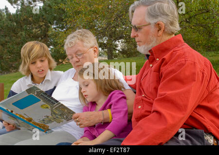 Großeltern und Enkelkinder auf Parkbank sitzen Stockfoto
