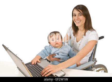 Mutter im Rollstuhl halten Baby während der Eingabe auf laptop Stockfoto