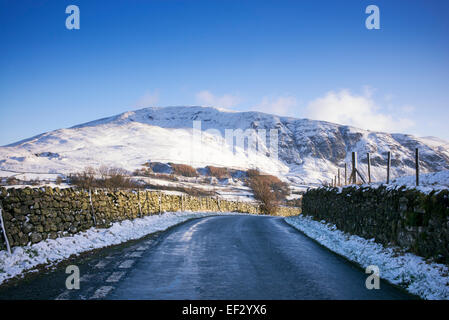 Straße auf der Westseite des Lakelandpoeten-Gebirges im Winterschnee. Seenplatte, Cumbria, England. Stockfoto