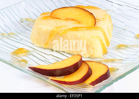 Herzförmige Pfirsich Bayerische Creme Dessert (Bavarese) mit Pfirsich-Sauce und Pfirsich Scheiben auf einer transparenten Glasplatte. Stockfoto