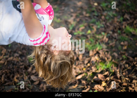 sonnendurchflutetes lächelndes Kind kopfüber hängend Stockfoto