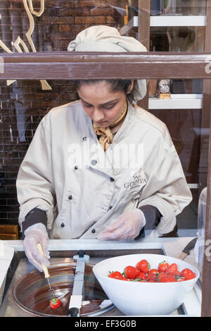 England, London, Covent Garden, Godiva Store, Frau, die Herstellung von Schokolade getaucht Erdbeeren Stockfoto