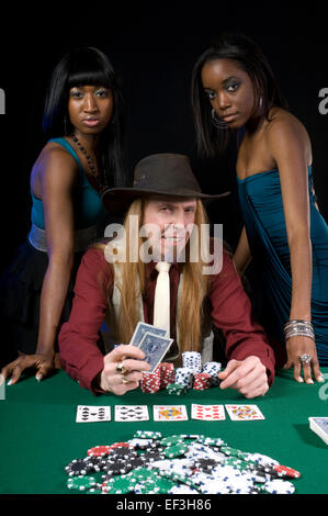 Zwei Frauen stehen hinter einem Mann Poker zu spielen Stockfoto