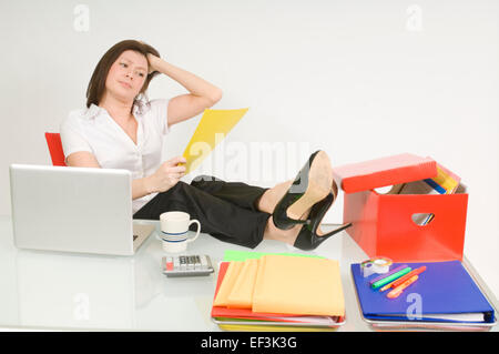 Geschäftsfrau, die mit ihren Füßen auf Schreibtisch sitzen Stockfoto