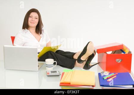 Geschäftsfrau, die mit ihren Füßen auf Schreibtisch sitzen Stockfoto