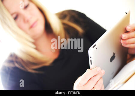 Blonde Haare weiße Frau am Schreibtisch mit Apple Ipad für Unternehmen arbeiten, helles Licht durchscheinen Stockfoto