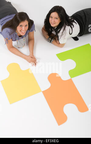 Zwei Frauen am Boden neben großen Puzzleteile liegen Stockfoto