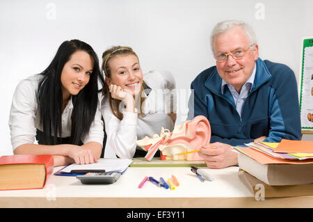 Lehrer zeigt Modell des menschlichen Ohres, zwei Studenten Stockfoto