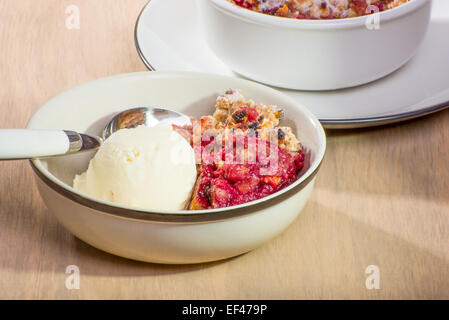 Frisch gebackene gemischte Beeren zerfallen in eine kleine Schale mit Vanilleeis serviert. Stockfoto