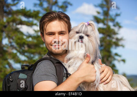 Junge Touristen lächelnden Mann mit Shih-Tzu Hund Portrait. Zeigt der Daumen nach oben Handsign. Stockfoto