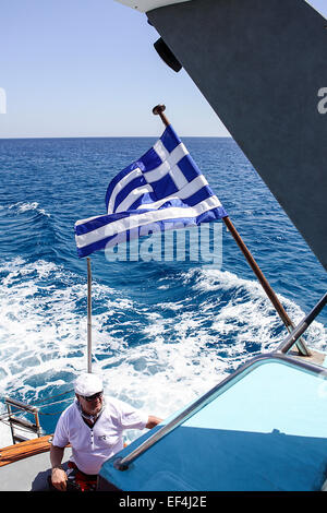 Darlehen-Tourist im hinteren Teil ein Kreuzfahrt-Schiff mit griechischen nationalen Flagge in der steifen Brise. Stockfoto