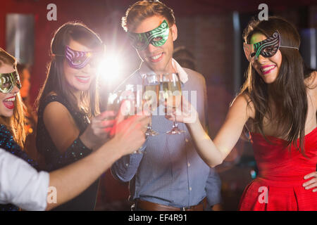 Freunde in Maskerade Masken Toasten mit Champagner Stockfoto