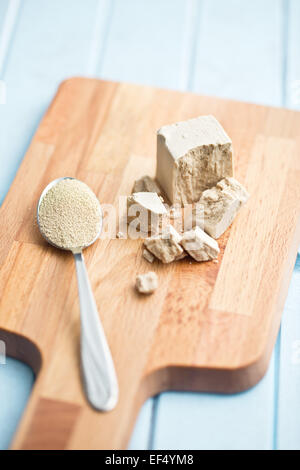 Frische und getrocknete Hefe auf Schneidebrett Stockfoto