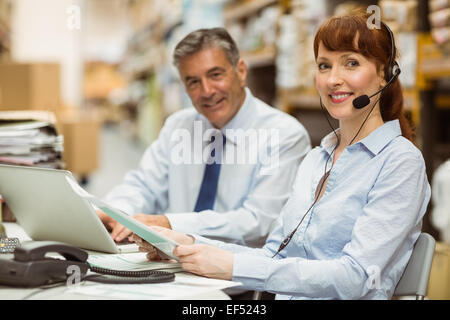 Lagerleiter, die Arbeiten an ihrem Schreibtisch tragen Kopfhörer Stockfoto