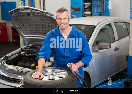 Lächelnde Mechaniker Aufpumpen des Reifens Stockfoto