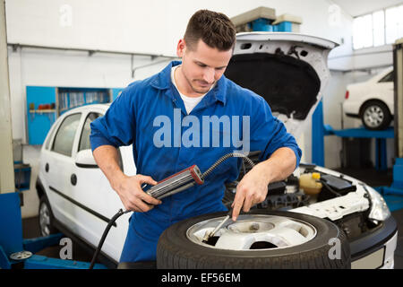 Fokussierte Mechaniker Aufpumpen des Reifens Stockfoto
