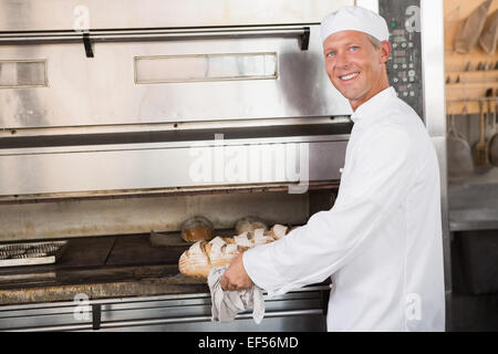 Glücklich Baker, die holding Tablett mit frischen Brötchen Stockfoto