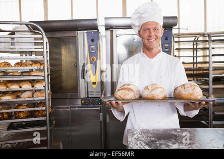 Glücklich Baker zeigt Tablett mit frischen Brötchen Stockfoto