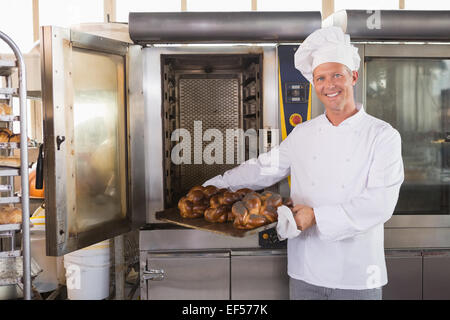 Glücklich Bäcker frisches Brot herausnehmen Stockfoto