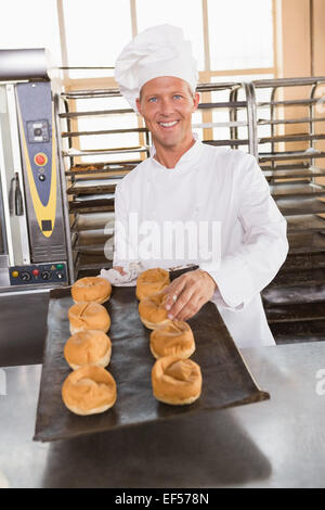 Glücklich Baker, die holding Tablett mit frischen Brötchen Stockfoto