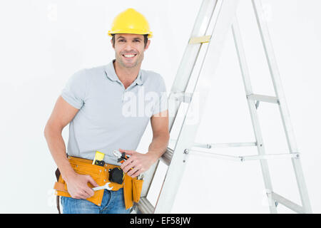 Arbeiter halten Werkzeuge und stützte sich auf Trittleiter Stockfoto