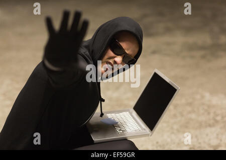 Stirnrunzelnd Hacker in Sonnenbrille gestikulieren Stockfoto