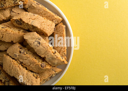 Blick auf einen Teller mit Cantuccini auf eine gelbe Tischplatte in der Nähe. Stockfoto