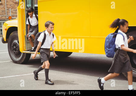 Niedliche Schulkinder aussteigen den Schulbus Stockfoto