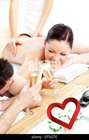 Zusammengesetztes Bild des jungen Liebespaar trinken Champagner liegend auf einem Massagetisch Stockfoto