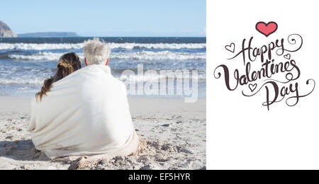 Zusammengesetztes Bild des Paares sitzen am Strand unter Decke Blick auf das Meer Stockfoto