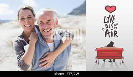 Zusammengesetztes Bild glücklich umarmt paar am Strand, Blick in die Kamera Stockfoto