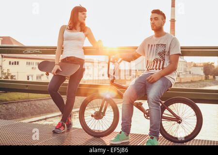 Junges Paar mit Skateboard und BMX Fahrrad ruht auf Brücke Stockfoto