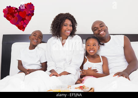 Zusammengesetztes Bild der glücklichen Familie mit Frühstück im Bett Stockfoto