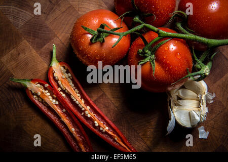 Tomaten, rote Chili und Knoblauch auf einem Schneidebrett Stockfoto