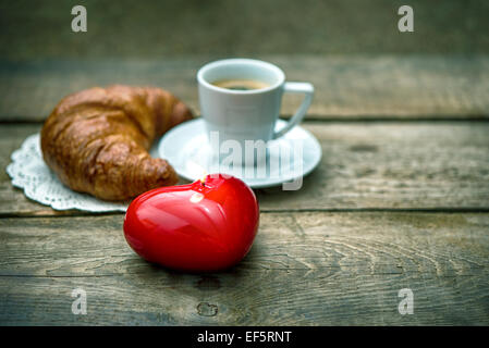 Rotes Herz Kerze, Tasse schwarzen Kaffee mit Croissant. Valentinstag-Konzept Stockfoto