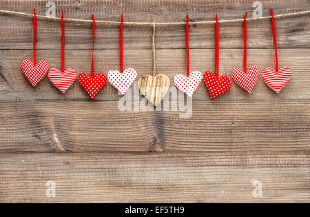 Rote Herzen hängen über hölzerne Hintergrund. Handgemachte Valentinstag Dekoration Stockfoto