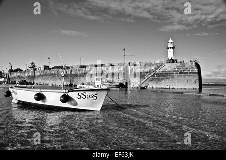 Die SS225 ruht friedlich in den seichten, kristallklaren Gewässern von St. Ives Hafen mit dem Leuchtturm, die gerade auf. Stockfoto