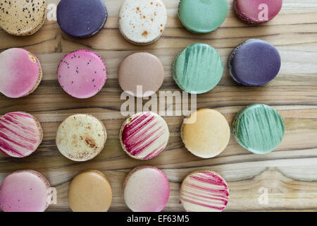 klassische französische Macarons handgefertigt und dekoriert in einer Vielzahl von Farben auf einem Holztisch Stockfoto
