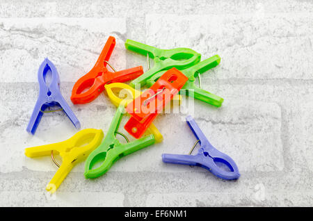 Reihe von bunten Wäscheklammern auf weiße Ziegel gemusterten Hintergrund Stockfoto