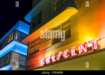 Crescent Hotel Art-Deco-gelbe Fassade beleuchtet in der Nacht durch die rote Leuchtreklame Deco Drive in Miami Beach, Florida USA Stockfoto