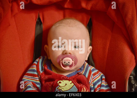 Ein kleines Mädchen mit einem Dummy in den Mund Stockfoto