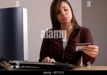 Eine junge Frau macht eine Geldkarte oder Kreditkarte Kauf von ihrem Computer zu Hause. Stockfoto