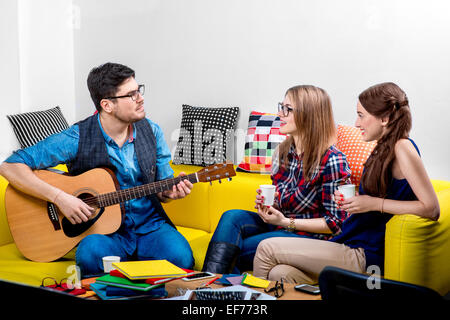 Mann, eine Gitarre mit Freundinnen Stockfoto