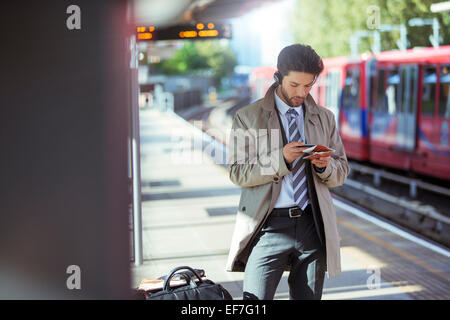 Geschäftsmann mit Handy im Bahnhof Stockfoto