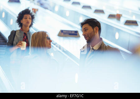 Business-Leute, die reden auf Rolltreppe Stockfoto