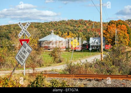 Malerische Landschaft des eine Runde Kuh Scheune und weißen Gehöft am Ende einer langen, Schmutz-Auffahrt im nördlichen Vermont, Vereinigte Staaten. Stockfoto