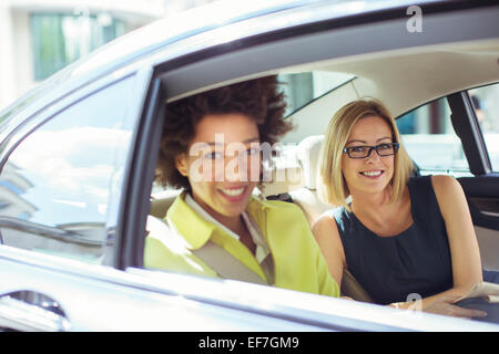 Geschäftsfrauen, die lächelnd im hinteren Sitz des Auto Stockfoto